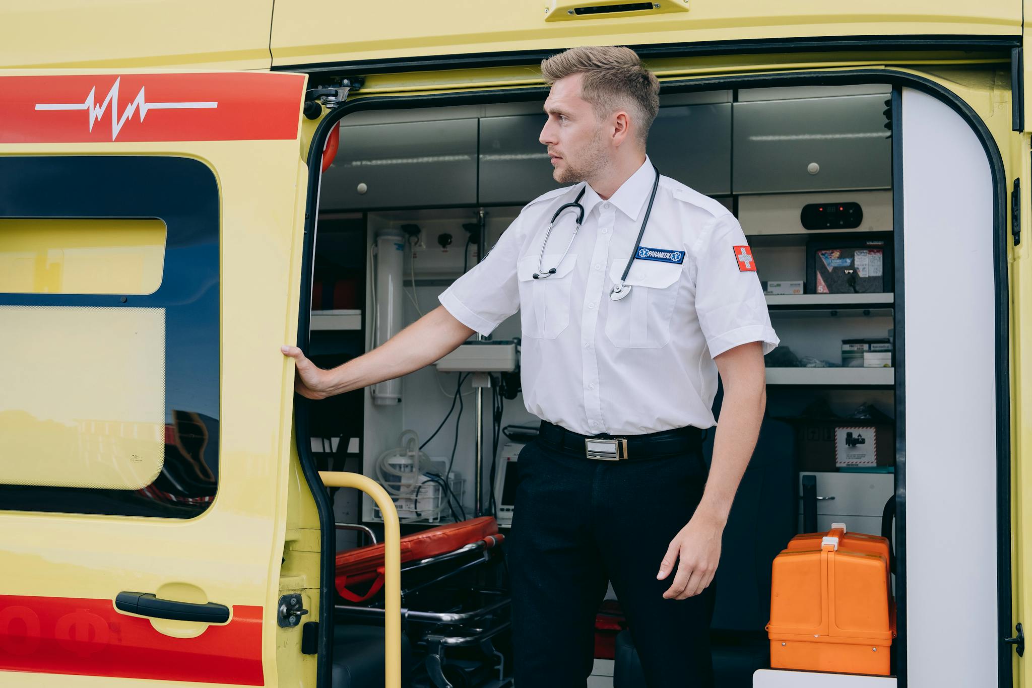 Paramedic standing by an ambulance, ready to assist in emergencies with medical equipment.