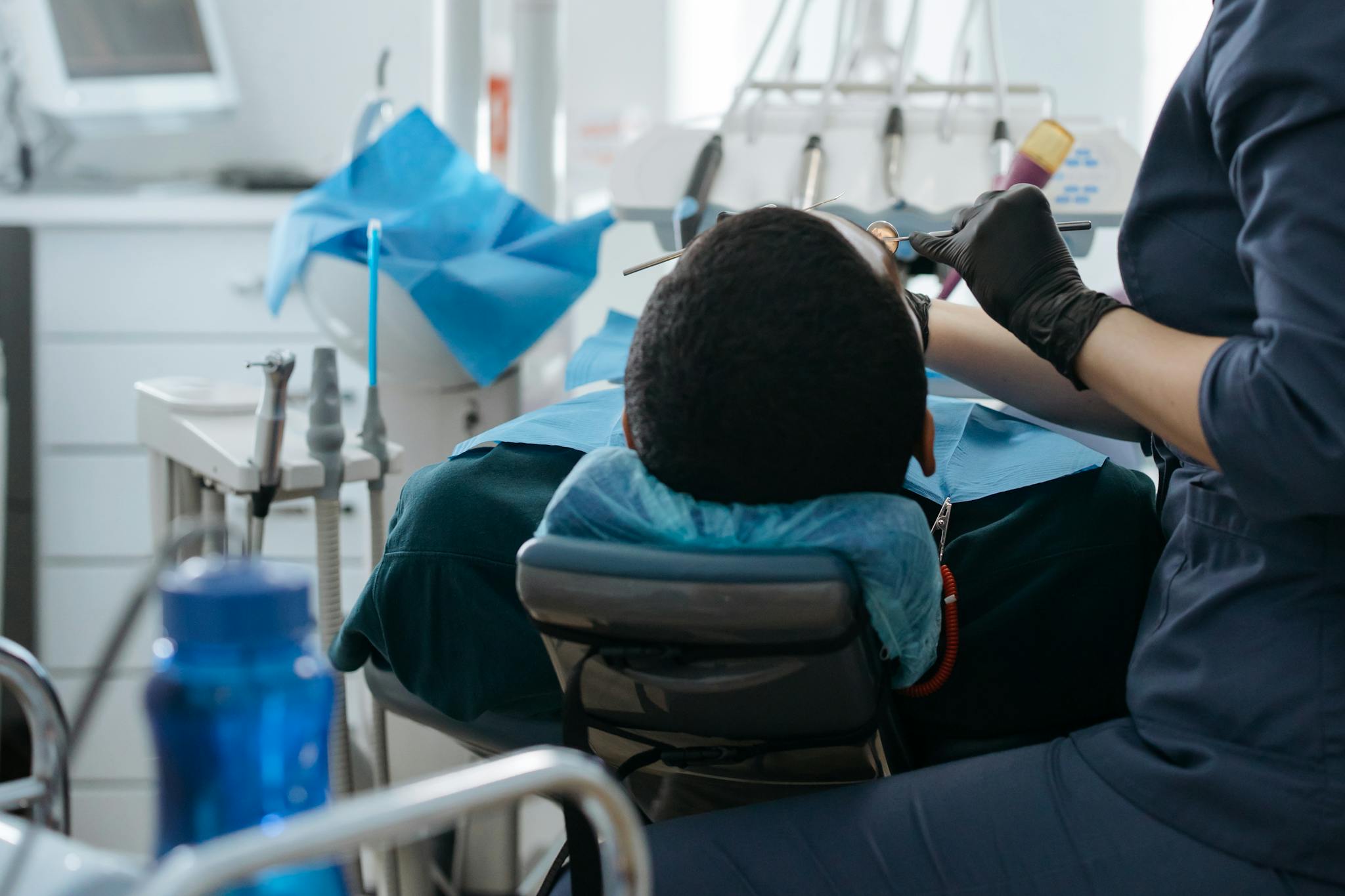 A dentist performing a checkup on a patient at a dental clinic, focusing on oral health.